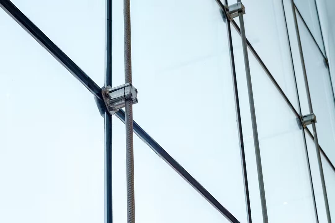 A close up of a structural glass facade with tension cable system and frosted glass panels